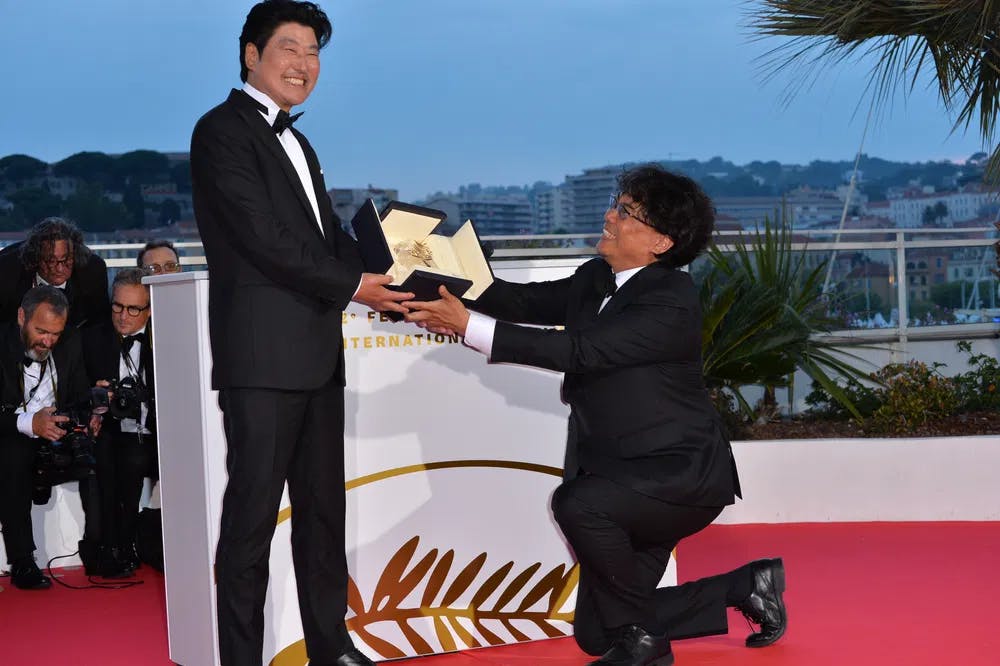 Palm bearers: "Parasite" director Bong Joon-ho and star Song Kang-ho celebrate winning Cannes' top prize. / Photo by Paul Smith, courtesy of Featureflash & Dreamstime.